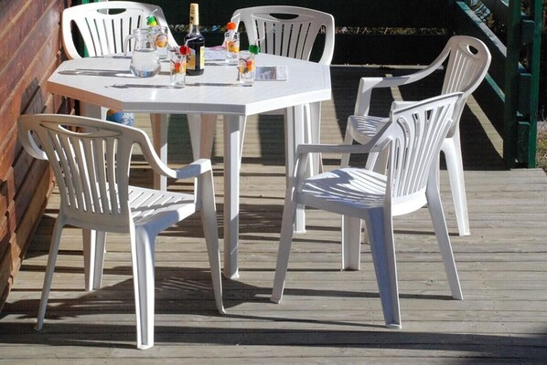 Una mesa y sillas blancas sobre una terraza de madera.