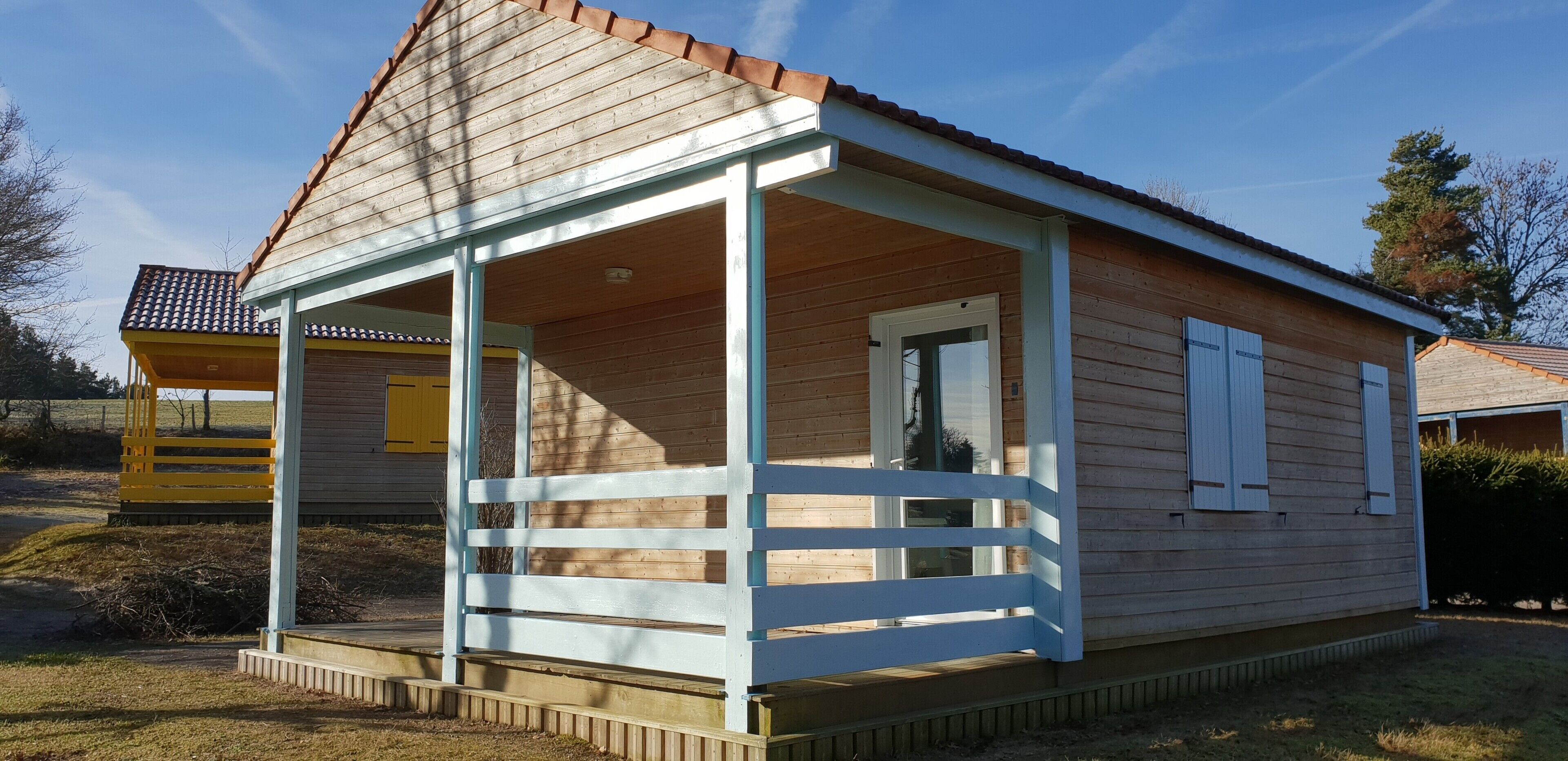 Een houten huis met een veranda, een deur en een raam.