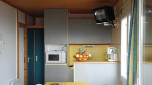 A compact kitchen with a microwave, a small coffee maker, and a fruit bowl on the counter. - Chalet Aster 1 with Mountain View, Shared Pool and Wi-Fi (BLAVIGNAC)