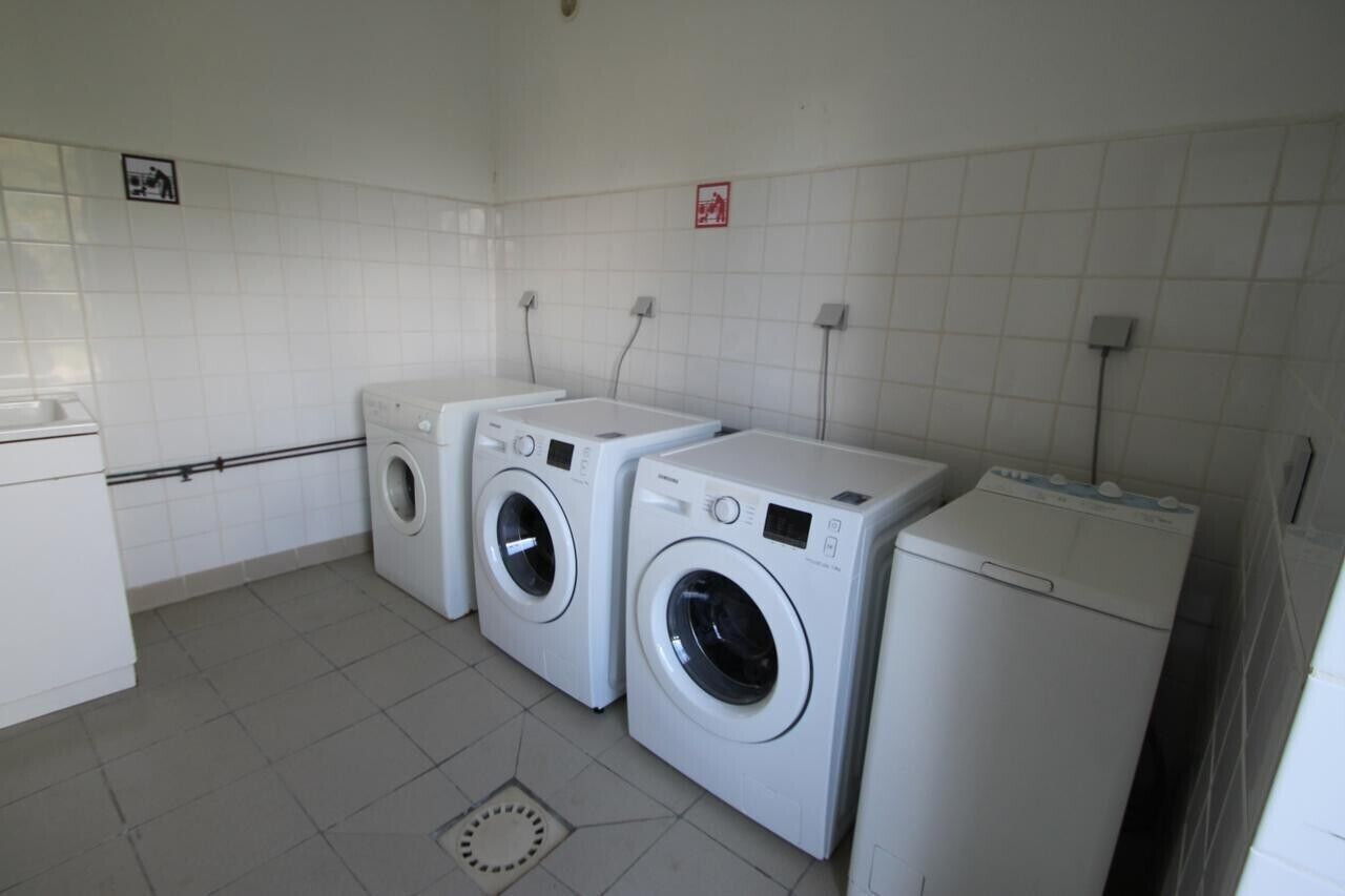 A laundry room with three washing machines and a dryer.