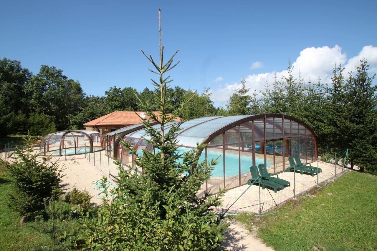 A glass-enclosed swimming pool area with lounge chairs.