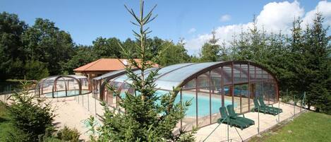 A glass-enclosed swimming pool area with lounge chairs.
