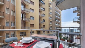 Un balcón con mesa lista para comer, con vistas a un edificio residencial con balcones.