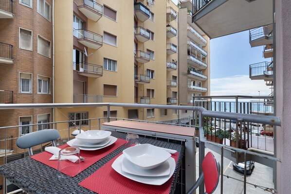 Un balcon avec une table dressée pour le dîner, donnant sur un immeuble d’habitation doté de balcons.