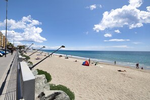 Une plage avec un ciel dégagé, une tente et des gens.