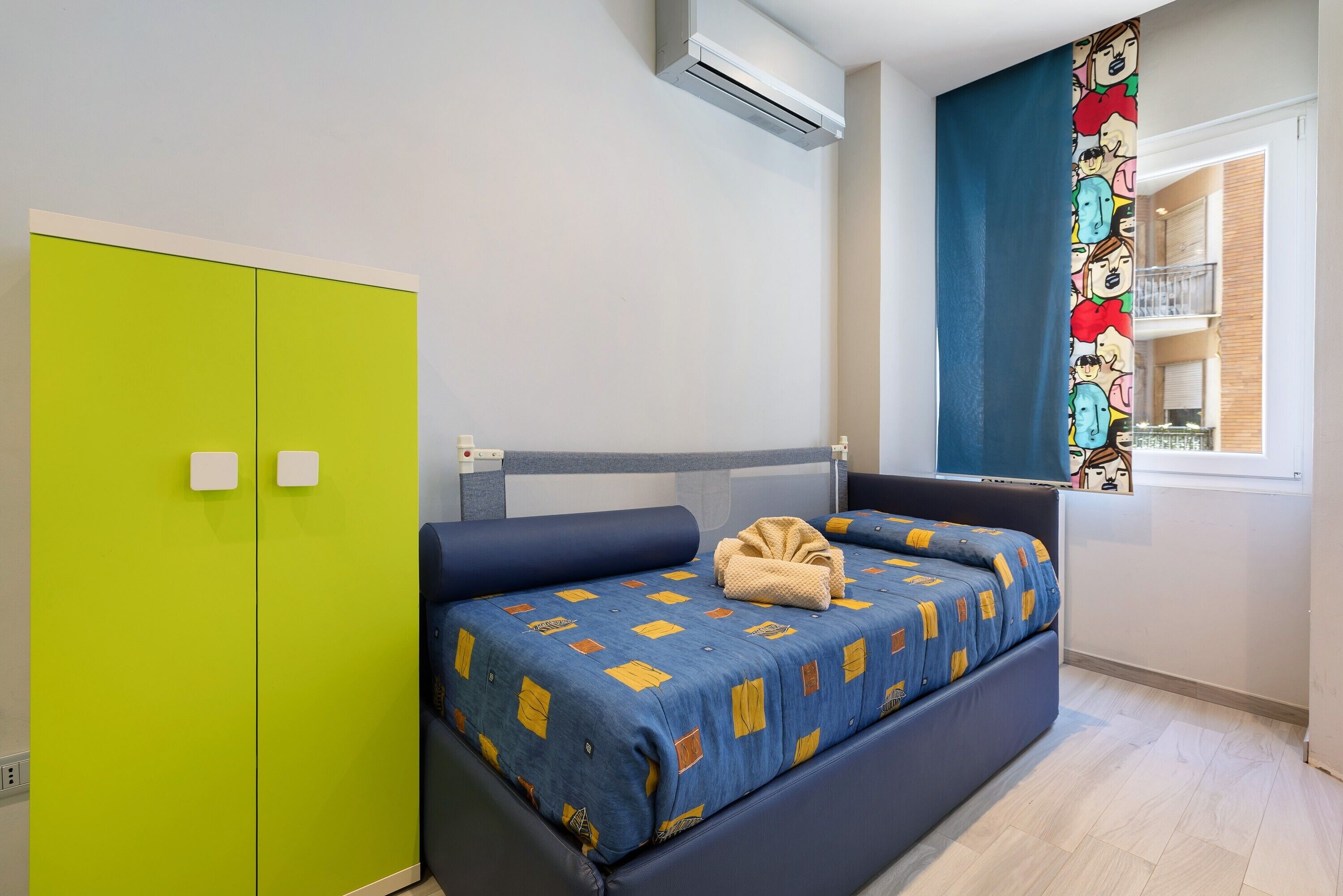 Une chambre à coucher avec un lit, une armoire verte et une fenêtre donnant sur un beau paysage.