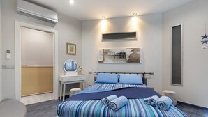 Un dormitorio moderno con una cama grande, mesitas de noche, un tocador y un aire acondicionado montado en la pared.