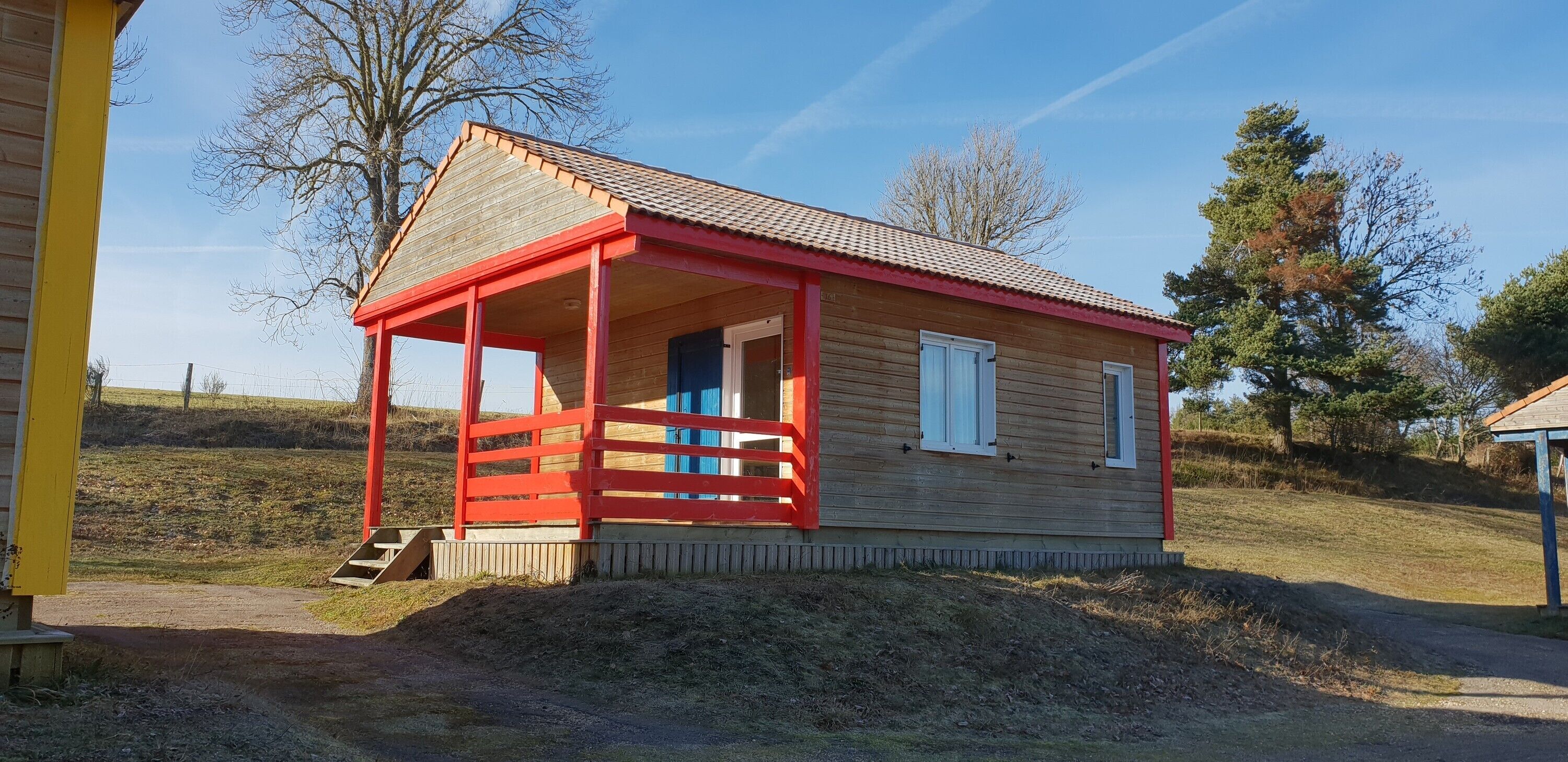 Une petite cabane en bois avec un porche rouge et une seule fenêtre.