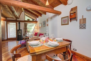 A wooden dining table set with plates, glasses, and a bottle, surrounded by wooden chairs. - Romito Lodge Apartment Mountain Retreat, Cesana Torinese, Italy (Cesana Torinese)