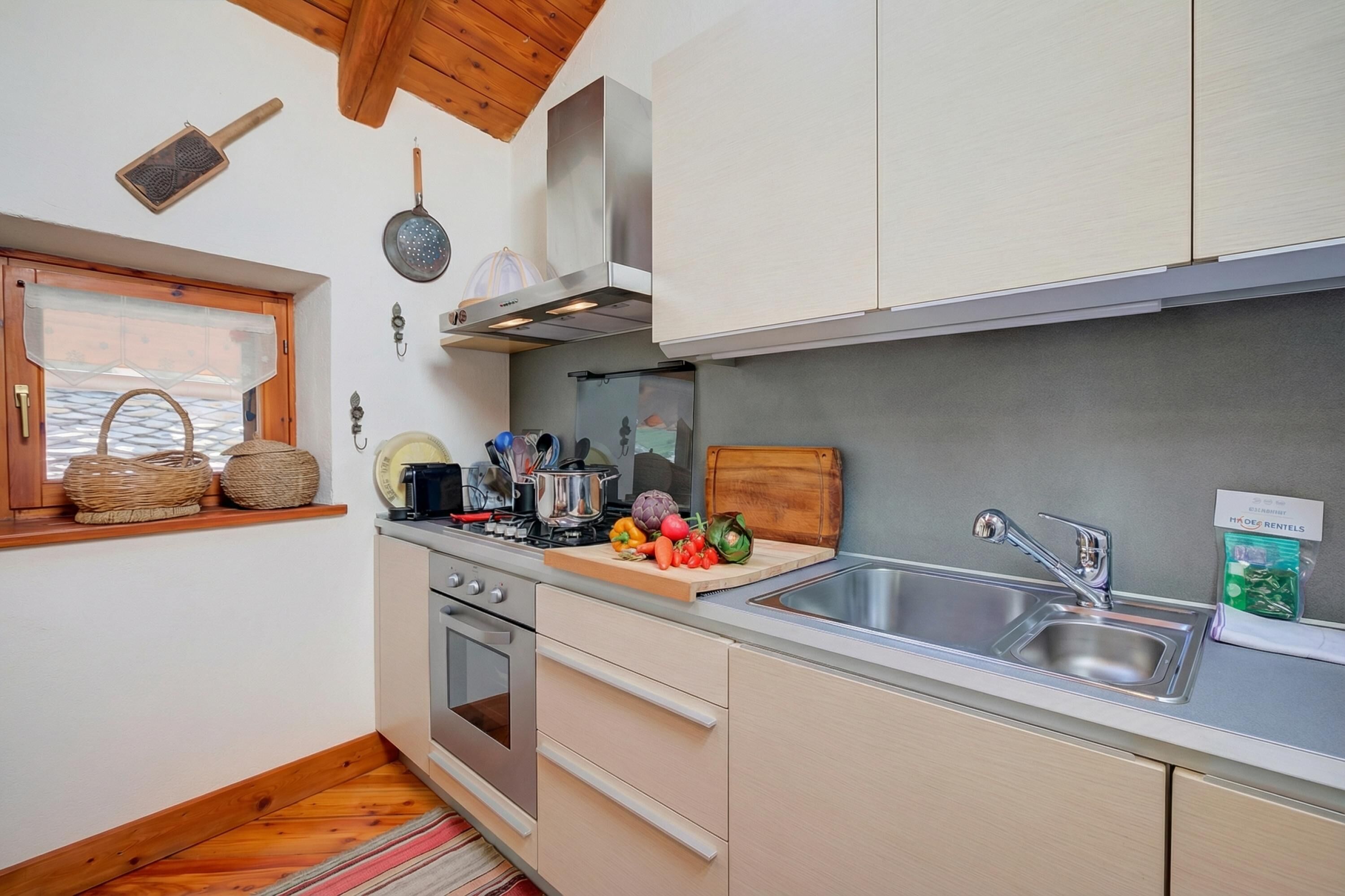 A modern kitchen with stainless steel appliances, a wooden window sill, and a variety of kitchen utensils.