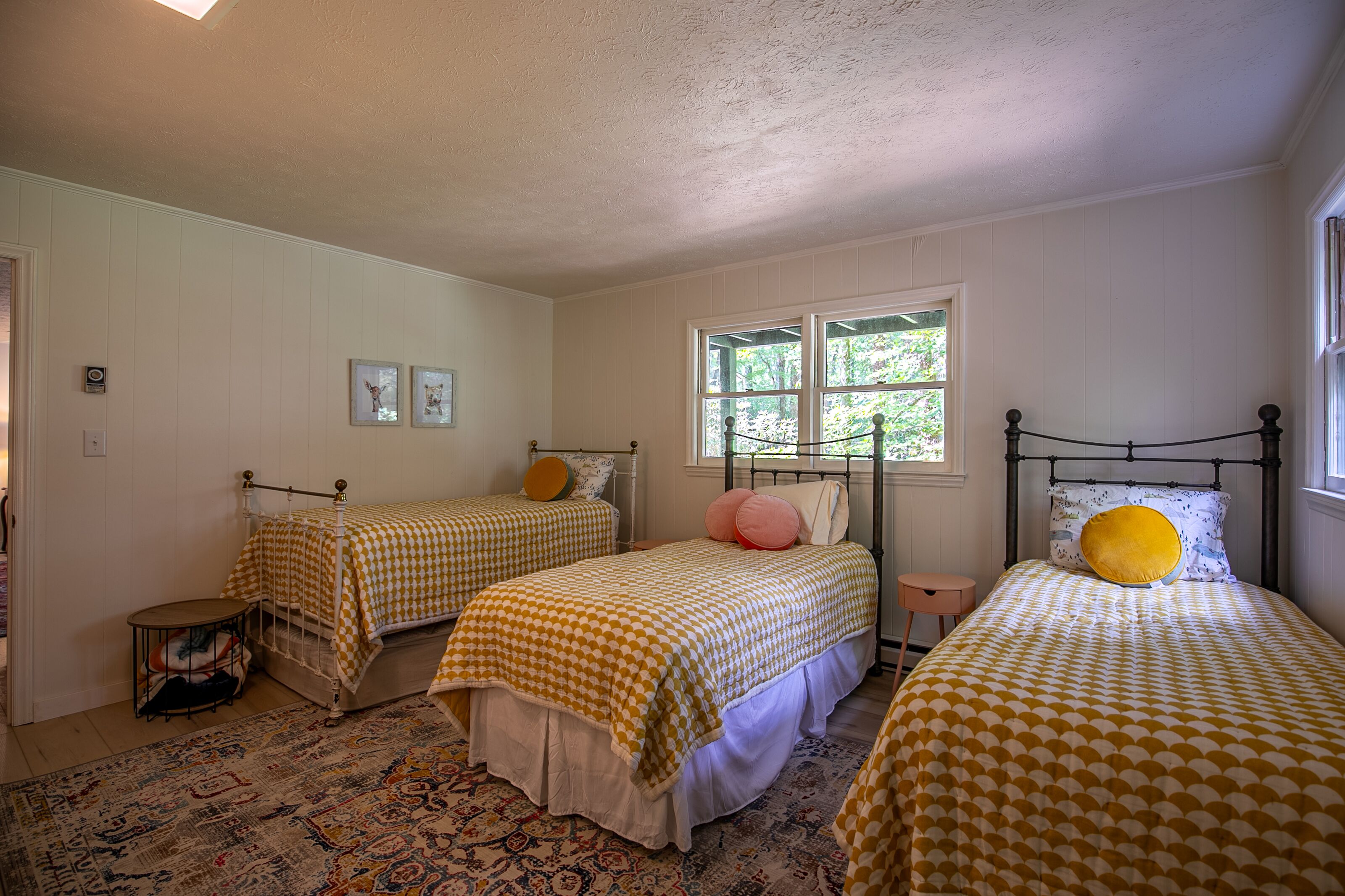 A room with two beds, a window, and a patterned rug.