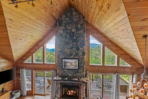Una cabaña con chimenea de piedra, ventanas amplias y un interior de madera.