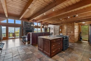 Una cocina amplia con una isla grande, piso de piedra y una chimenea.