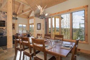 Una mesa de comedor de madera con sillas, una araña y una chimenea de piedra.