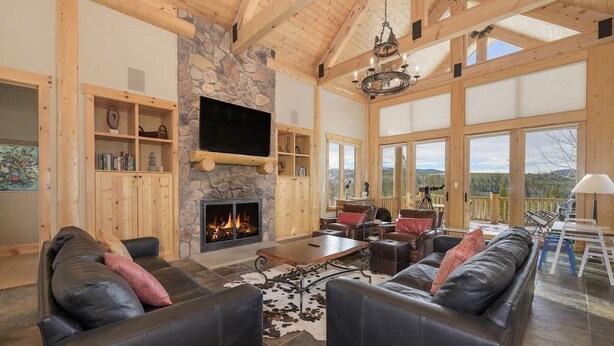 A spacious living room with a stone fireplace, leather sofas, and a large TV.