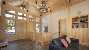 A spacious room with a black leather sofa, wooden walls, and a large window.
