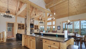 A spacious kitchen with wooden beams, a large island, and a dining area with a view.