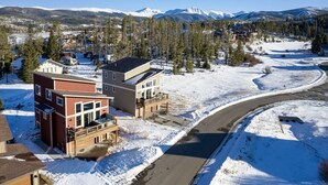 A residential area with modern houses, a winding road, and snow-covered mountains in the background. - 58 Elk Ranch | 4BR Hot Tub, Byers Peak Views (Fraser)