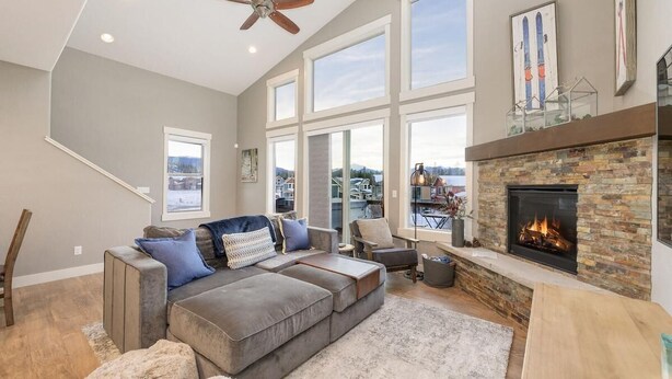 A spacious living room with a large gray sectional sofa, a fireplace, and a view of the outside. - 58 Elk Ranch | 4BR Hot Tub, Byers Peak Views (Fraser)