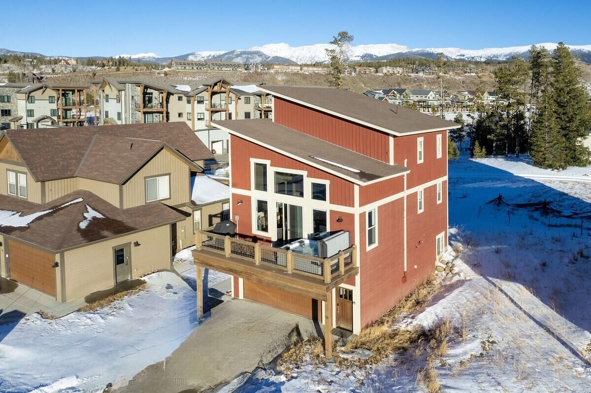 A residential building with a balcony, a garage, and a view of snow-covered mountains.