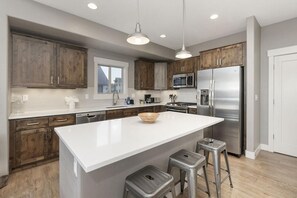 A modern kitchen with wooden cabinets, stainless steel appliances, and a large island with stools.