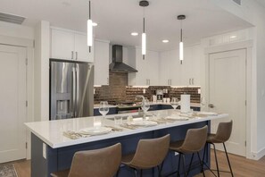 A modern kitchen with a central island, white cabinetry, and a brick backsplash.