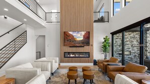 A modern living room with a fireplace, sofas, and a large TV. - Scenic Sunvilla Monthly Home| Private Pool, Hot Tub, Basketball Court (Hurricane)