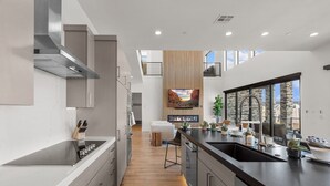 A modern kitchen with a central island, built-in appliances, and a large window offering a view of the city. - Scenic Sunvilla Monthly Home| Private Pool, Hot Tub, Basketball Court (Hurricane)