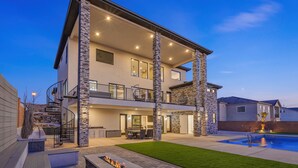 A modern two-story house with a stone facade, a pool, and a well-lit outdoor area. - Scenic Sunvilla Monthly Home| Private Pool, Hot Tub, Basketball Court (Hurricane)