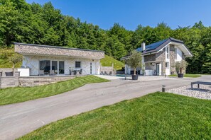 A modern two-story house with a stone facade, a swimming pool, and a well-maintained lawn.