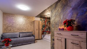 A modern living room with a grey sofa, a wooden cabinet, and a small table with a red flower vase. - Wellness & Relax Apartment Lilly, Trebnje, Slovenia (Trebnje)