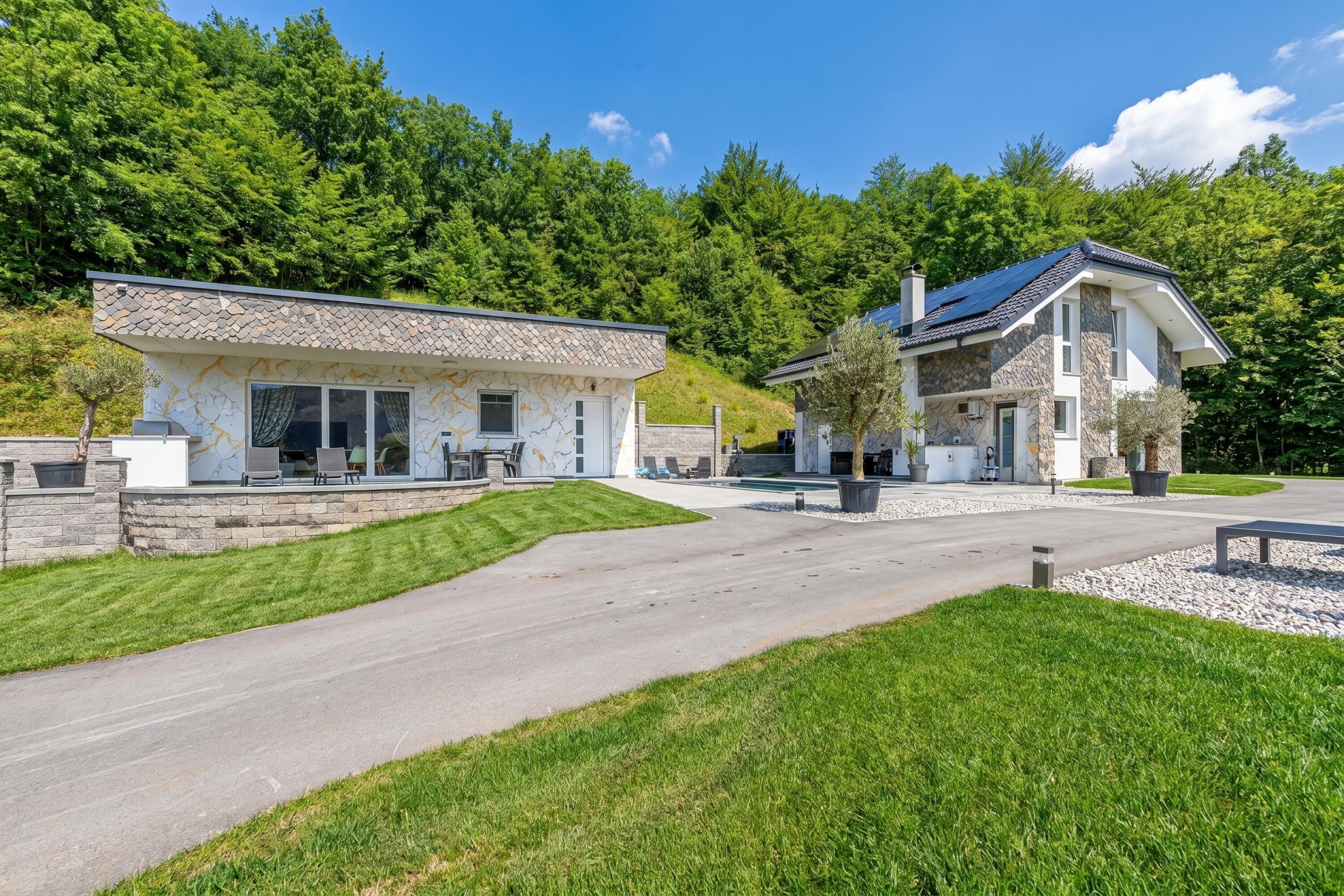 A modern house with a stone facade, a driveway, and a well-maintained lawn.