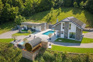 A modern house with a swimming pool, stone exterior, and a wooden deck. - Wellness Paradise House Tim, Trebnje, Slovenia (Trebnje)