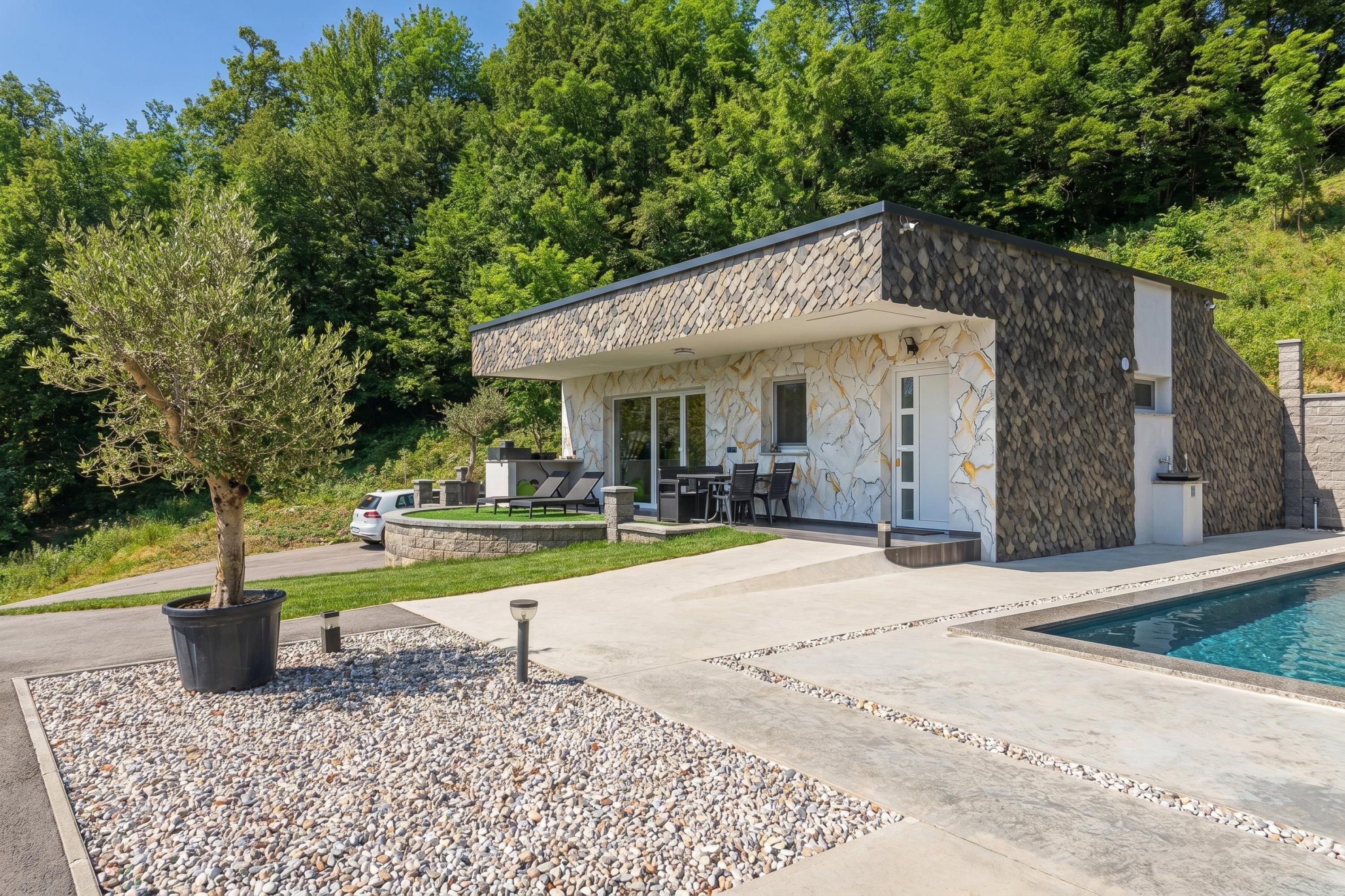 Una casa moderna con piscina, mobiliario exterior y un gran árbol.