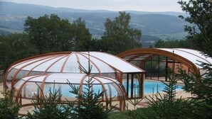 Zwei kuppelartige Gebäude mit Glasdächern, vermutlich als Unterkunft genutzt, umgeben von Grünflächen und einem Pool.