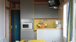 Een kleine keuken met een magnetron, een fruitschaal en een koffiezetapparaat.