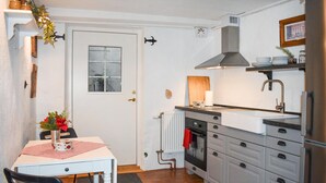 A compact kitchen with a white door, a small window, a built-in oven, a sink, and a refrigerator.