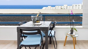 A balcony with a table set for two, a champagne bottle, and a potted orchid. - Beautiful Studio in front of the sea in Costa Adeje (Adeje)