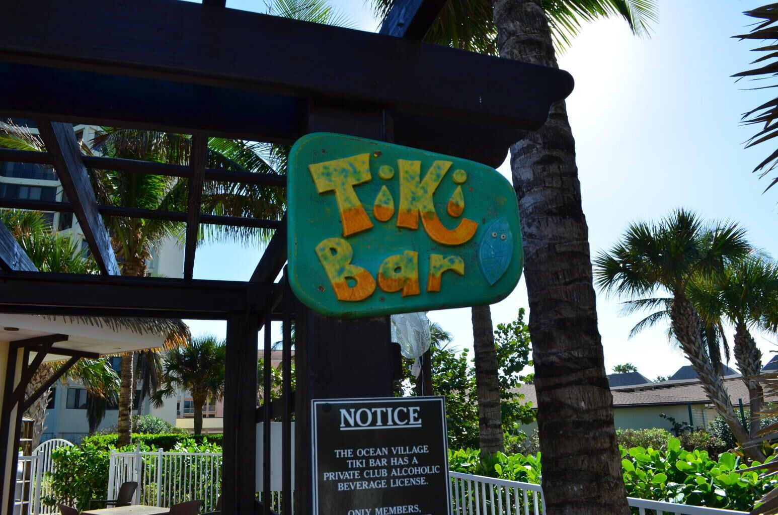 A Tiki Bar sign with a notice about The Ocean Village's private club license.