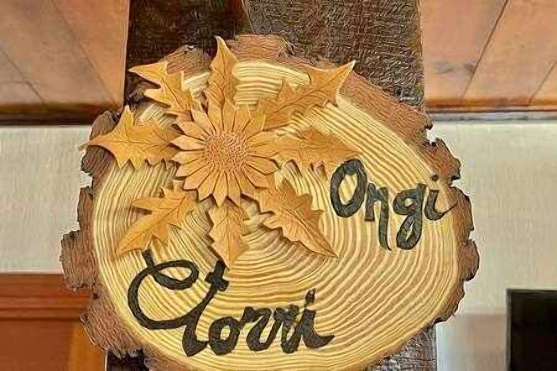 Une enseigne en bois ornée de feuilles sculptées, sur laquelle est inscrit le nom « Ongi ».