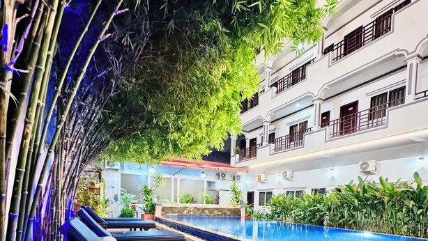 Un espace aménagé au bord de la piscine, avec des chaises longues, une piscine et un bâtiment doté de balcons.