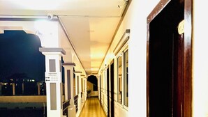 Un couloir doté d’un plancher en bois, de murs blancs et de portes situées sur le côté droit.