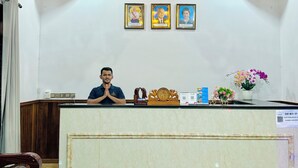 Un comptoir d’accueil avec une horloge, des photos encadrées et une plante en pot.