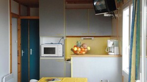 A compact kitchen with a microwave, a fruit bowl, and a coffee maker. - Chalet Fougère with Mountain Views, Shared Pool, and Wi-Fi (Blavignac)