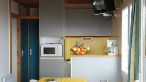 Een kleine keuken met een magnetron, een fruitschaal en een koffiezetapparaat.