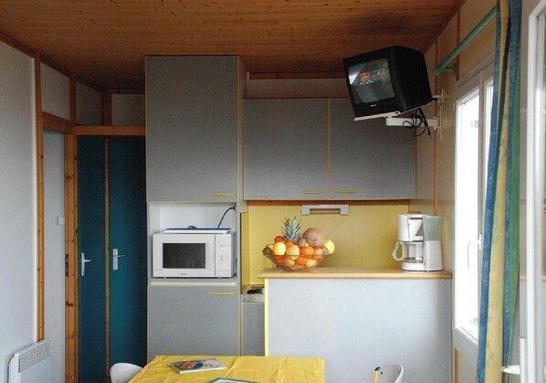 A compact kitchen with a microwave, a fruit bowl, and a coffee maker. - Chalet Ancolie with Mountain View, Shared Pool, and Wi-Fi (Blavignac)