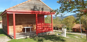 Een houten chalet met een rode veranda en een kleine tafel.