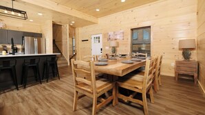 Un interno in legno con un tavolo da pranzo per quattro persone, angolo cottura con frigorifero e una scala che conduce a un altro livello.