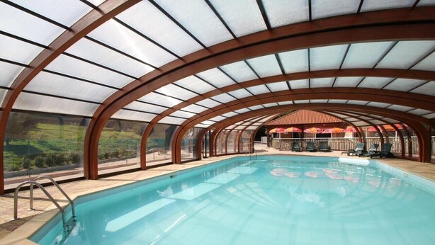 Una piscina interior con techo de vidrio y vistas al exterior.