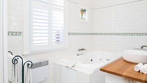 Ein Badezimmer mit einer Badewanne, einem Waschbecken und einem Fenster mit Jalousien.